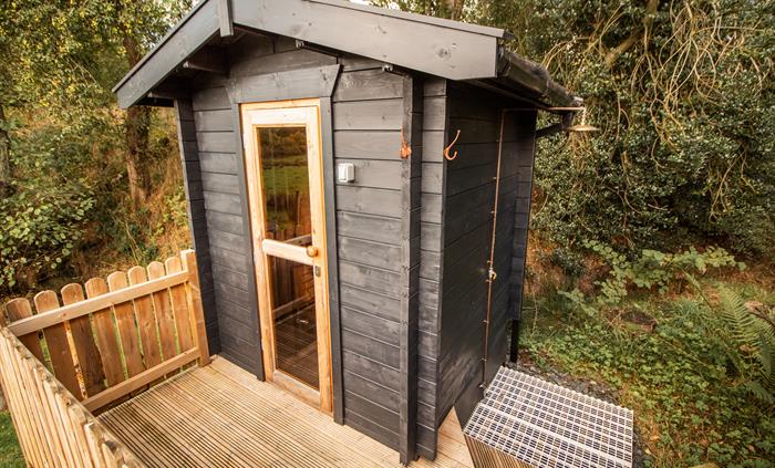 Private wood fired sauna area with robes and an outdoor cold water shower.